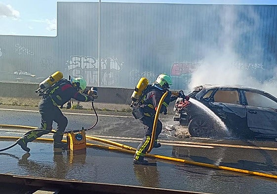 Los bomberos sofocan el incendio en el vehículo.