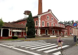 Una vecina camina junto al edificio principal de La Lechera, este verano, en Torrelavega.