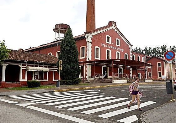 Una vecina camina junto al edificio principal de La Lechera, este verano, en Torrelavega.