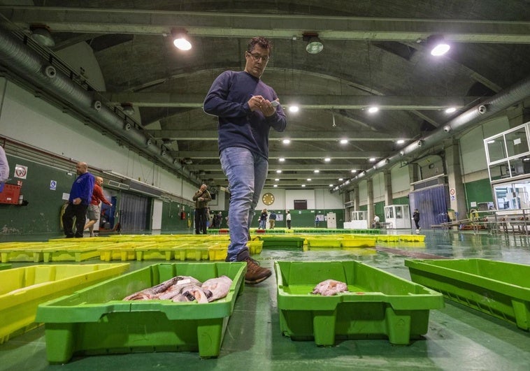 En la lonja. Antes de entrar a la sala de subastas, los compradores examinan el pescado que se encuentra disponible ese día y toman nota de las posibles compras a realizar durante el momento de la puja. En la fotografía, Unai Martín prepara su lista.