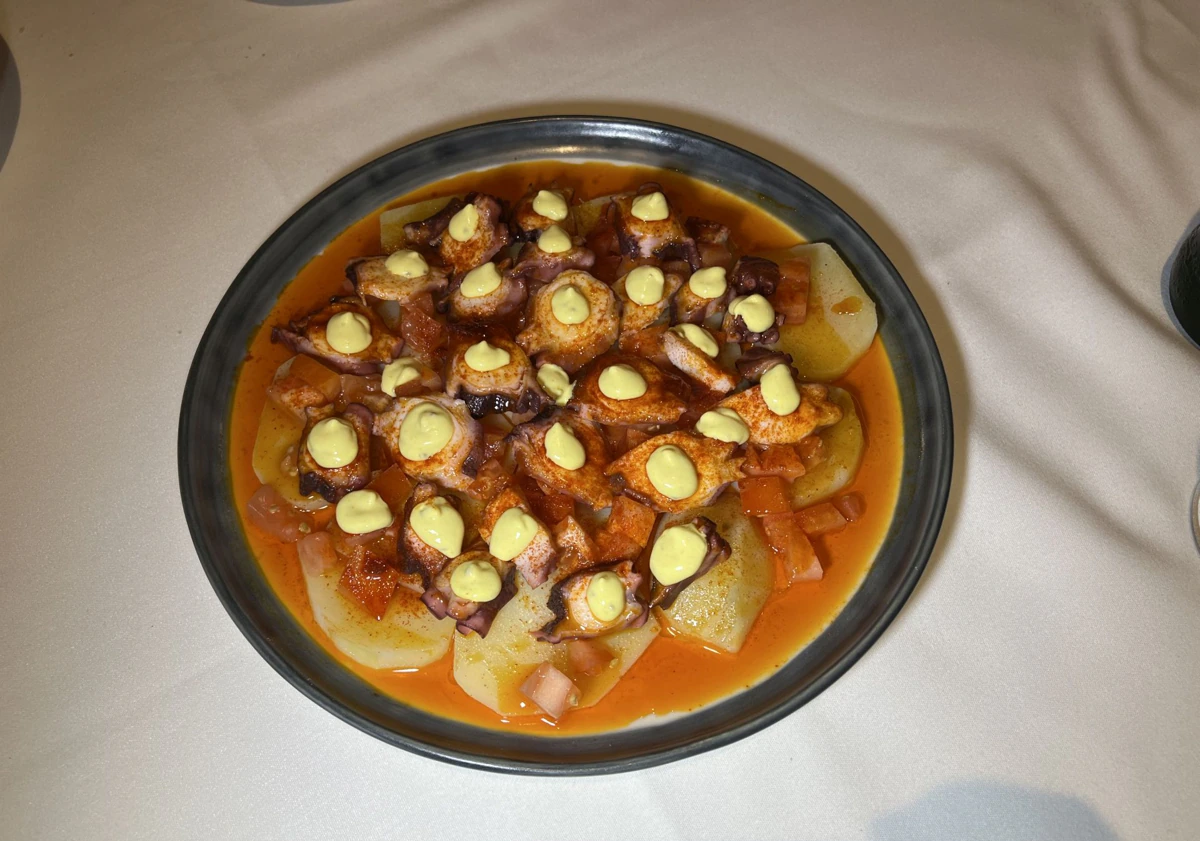 Imagen principal - Marián muestra la paella al cliente antes de servir. Arriba, pulpo gallego con fondo y mostaza, y profiteroles de queso de cabra y foie.