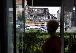 La camarera de una cafetería que se encuentra frente al edificio derrumbado, observa los escombros que quedaron tras el incendio.