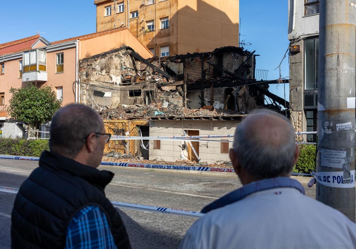 Dos vecinos observan los restos del edificio que ardió en la madrugada del sábado.