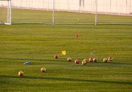 Unos balones de fútbol ocupan el centro de un campo de entrenamiento.