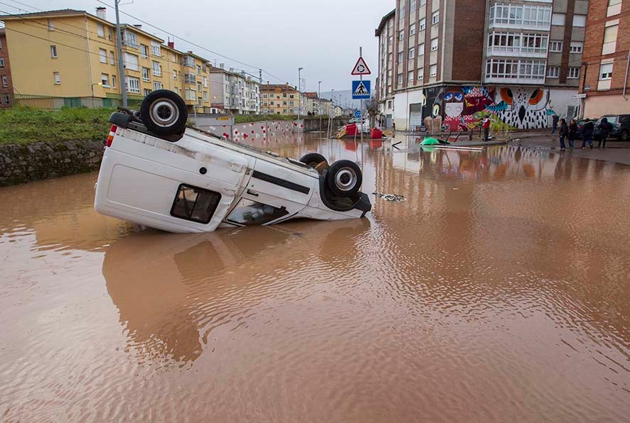 Imagen de un coche volcado en las calles anegadas de Reinosa, donde en 2019 se registró una de las inundaciones históricas de Cantabria, y una de las más recientes, tras el desbordamiento del Híjar y el Izarilla. El agua llegó a las calles y bajos de las casas.