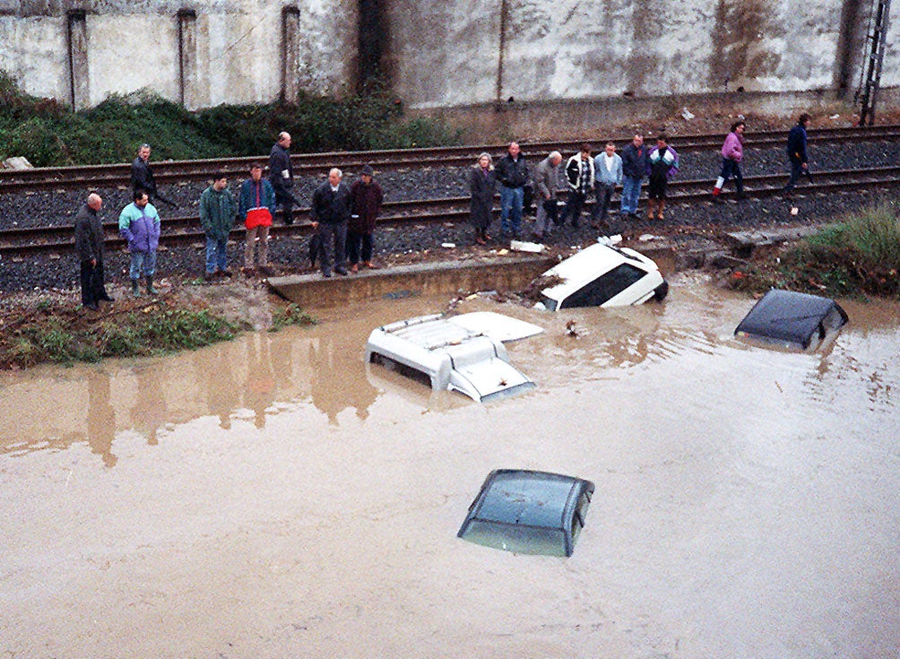 Coches completamente sumergidos bajo el agua y junto a las vías del tren en la calle José María de Pereda tras las inundaciones por el fuerte temporal de diciembre de 1996.