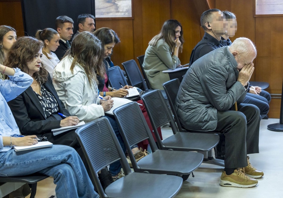 El acusado tapa su rostro ante los medios de comunicación y el público.