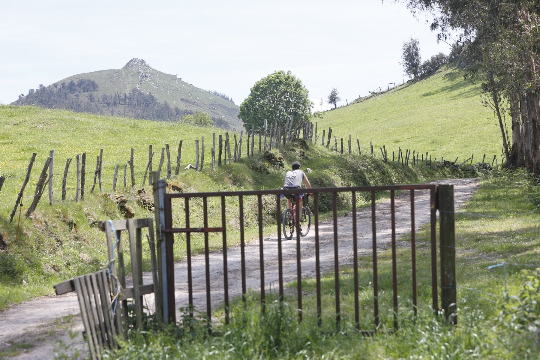 Un ciclista circula por un camino de la sierra del Dobra con el pico La Capía al fondo.