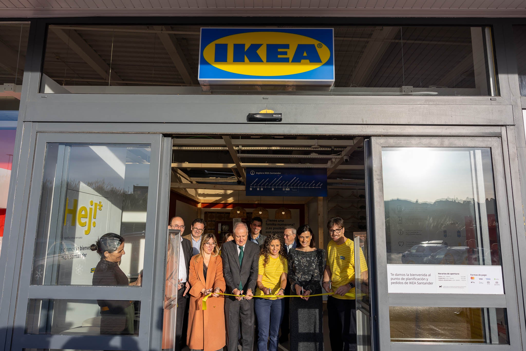 Autoridades y miembros del personal de Ikea cortan la cinta de reapertura.