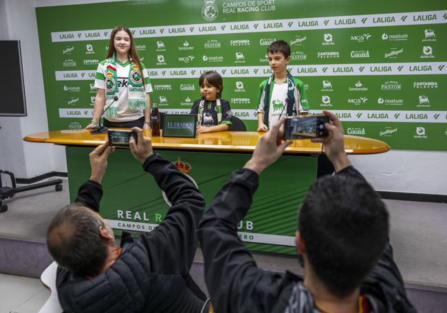 Elena Achurra y Daniel y Saúl Muñiz posan en la sala de prensa del Racing mientras sus padres ejercen de periodistas y les toman fotografías.