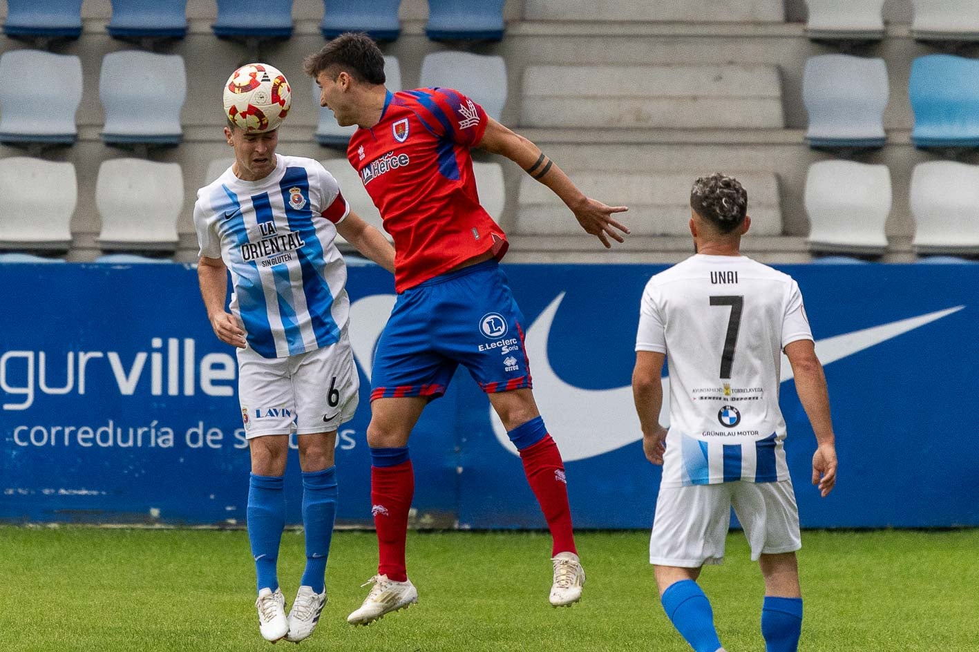 Alberto Gómez cabecea junto a un rival, con Unai presenciando la jugada.