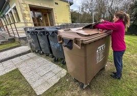 Una vecina de Piélagos deposita biorresiduos en un contenedor marrón instalado en el municipio.