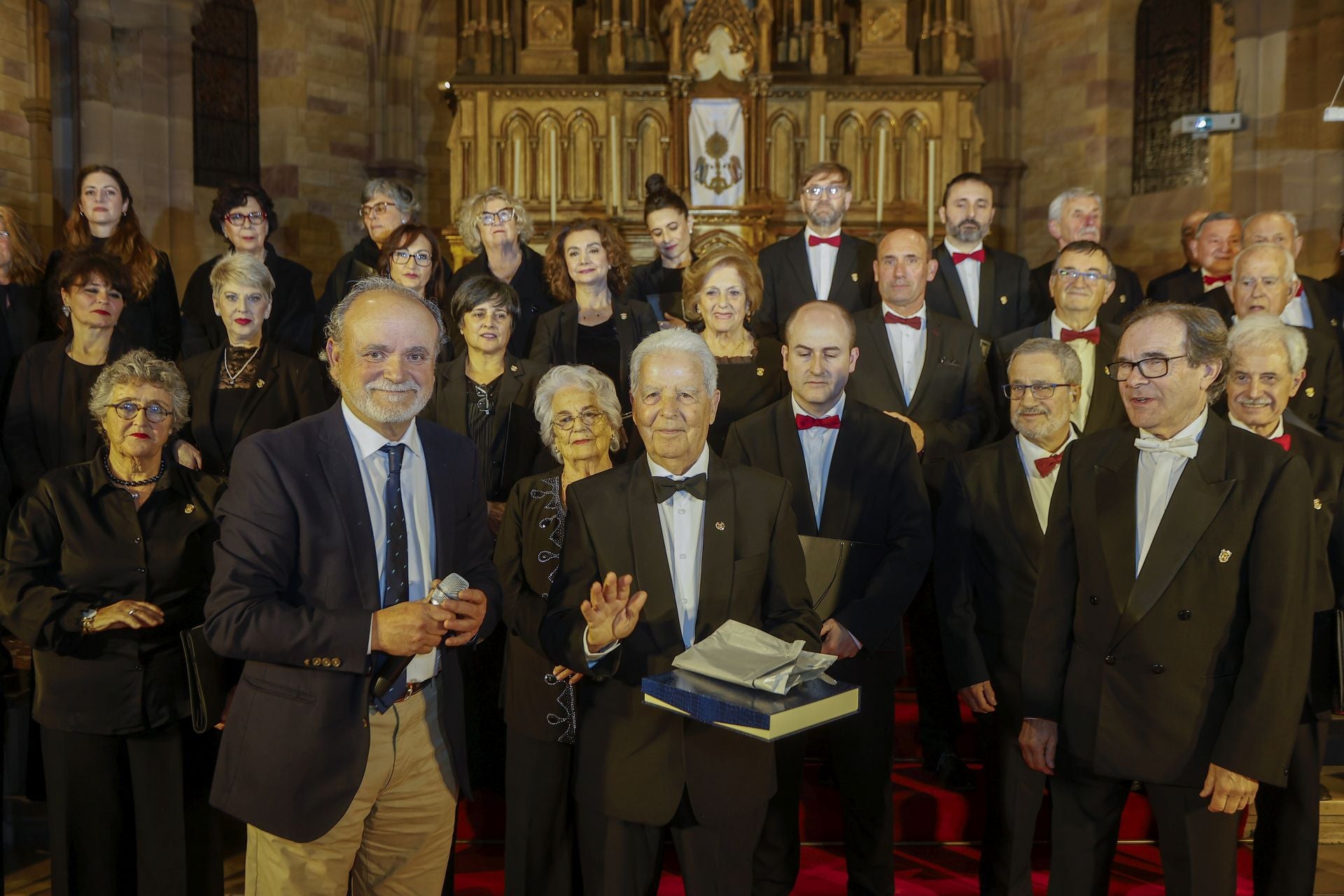 El homenajeado recibe un obsequio de la Coral de Torrelavega.