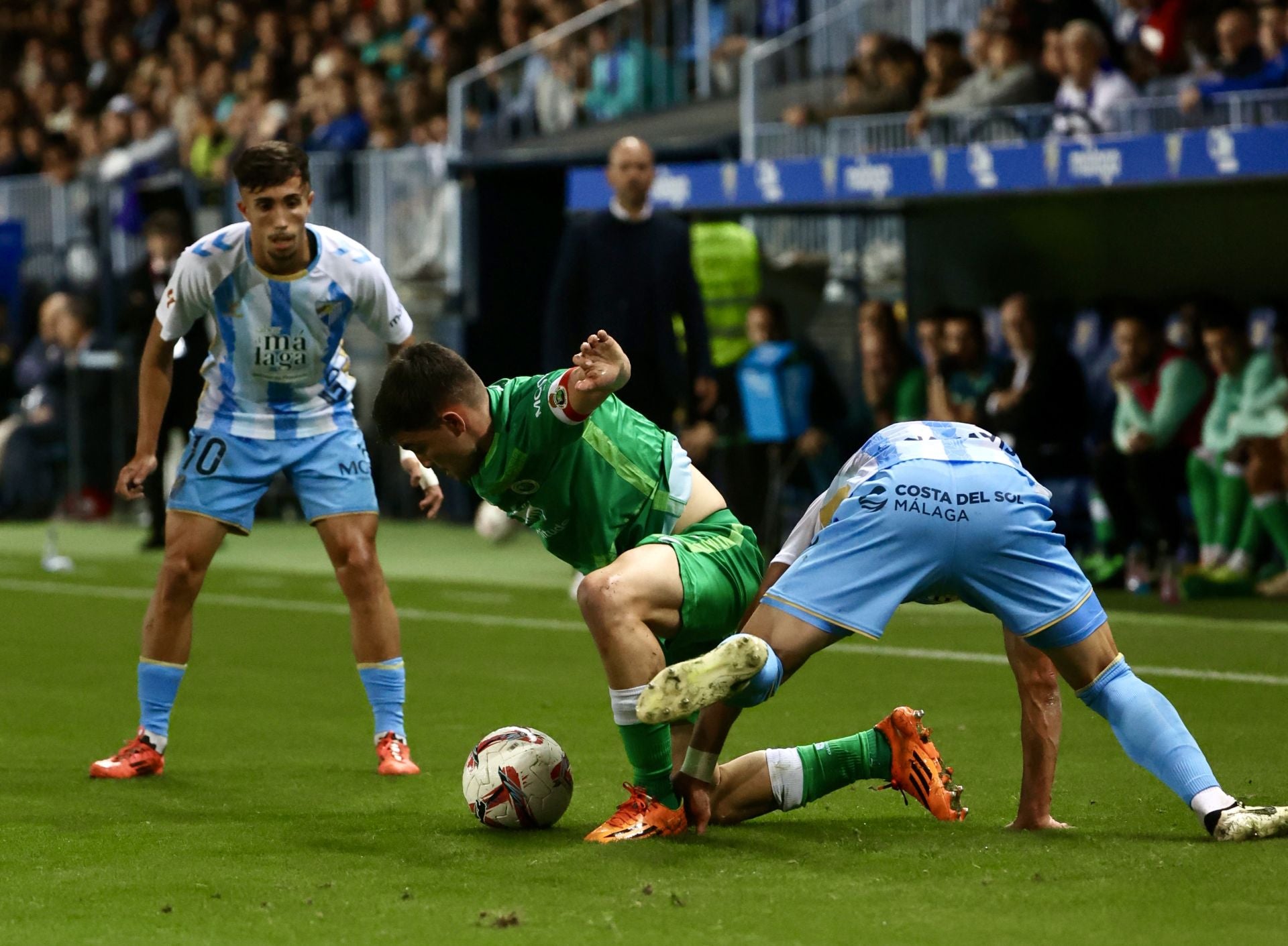 El racinguista Mario García pelea por mantener el balón ante dos jugadores del Málaga.