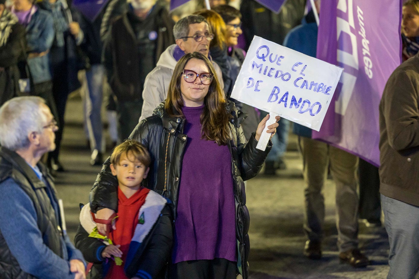 Una madre junto a su hijo porta una pancarta en la que se lee «Que el miedo cambie de bando».