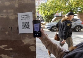 Una vecina escanea el código QR de uno de los carteles de la campaña, promovida por la Concejalía de Igualdad del Ayuntamiento.