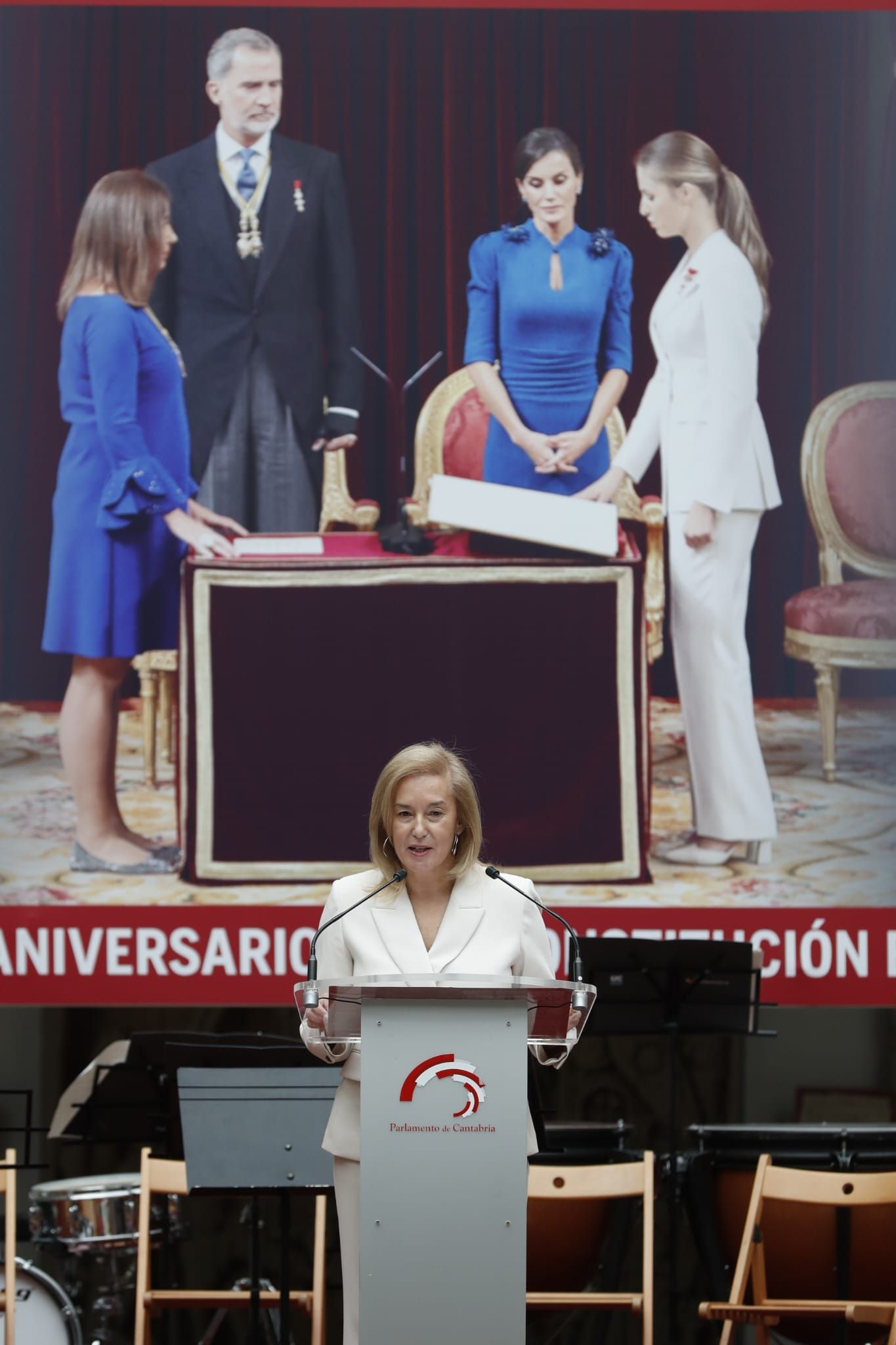 La presidenta del Parlamento de Cantabria, María José González Revuelta, durante el discurso que ha ofrecido en el patio del Parlamento de Cantabria. Al fondo, la imagen de la princesa Leonor jurando la Constitución. 