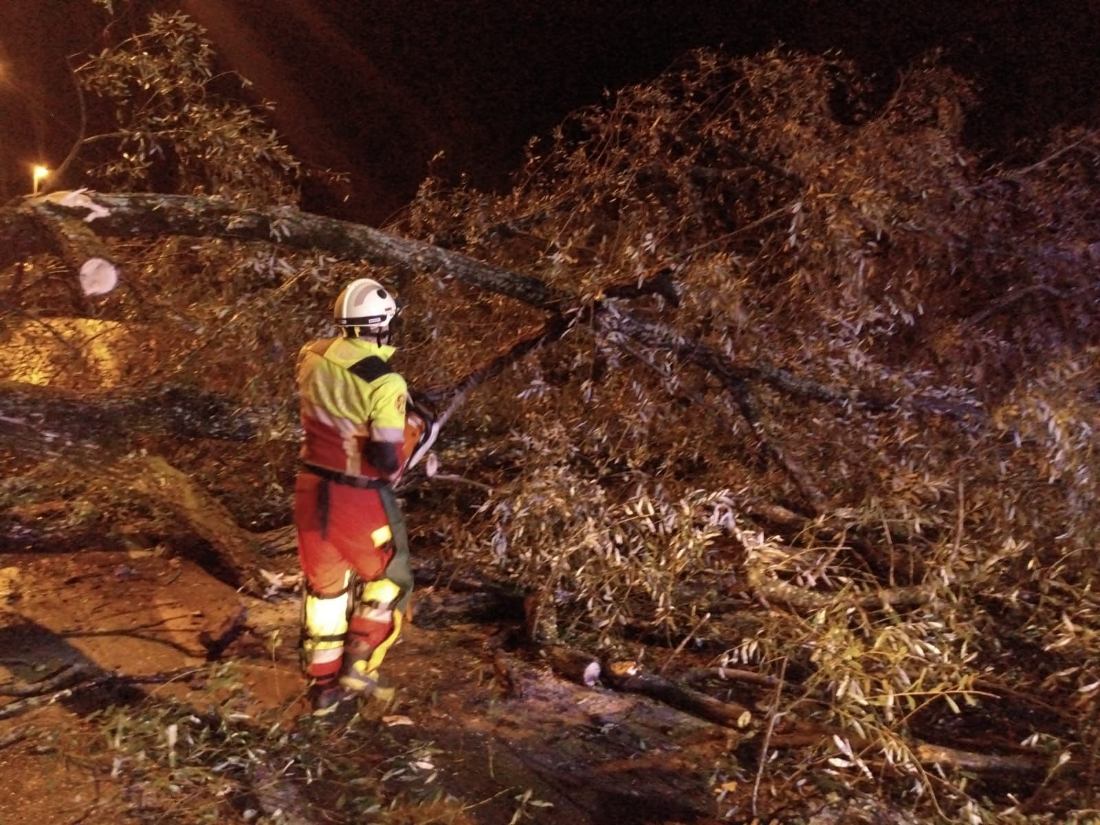 Un bombero, trabajando esta noche para despejar la carretera entre Sarón y La Penilla.