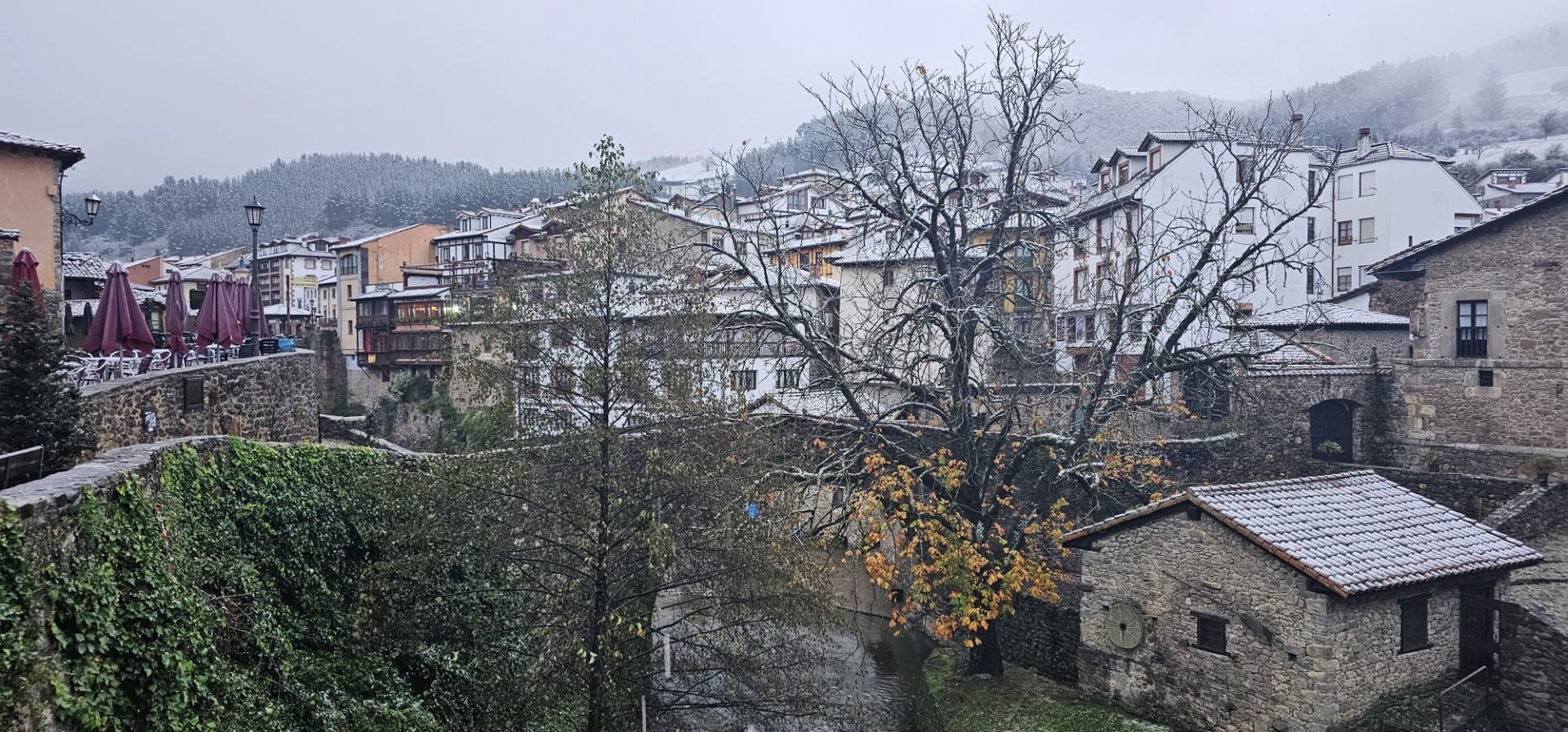 El río, el puente, las terrazas y las casas de Potes, bajo una fina capa de nieve.