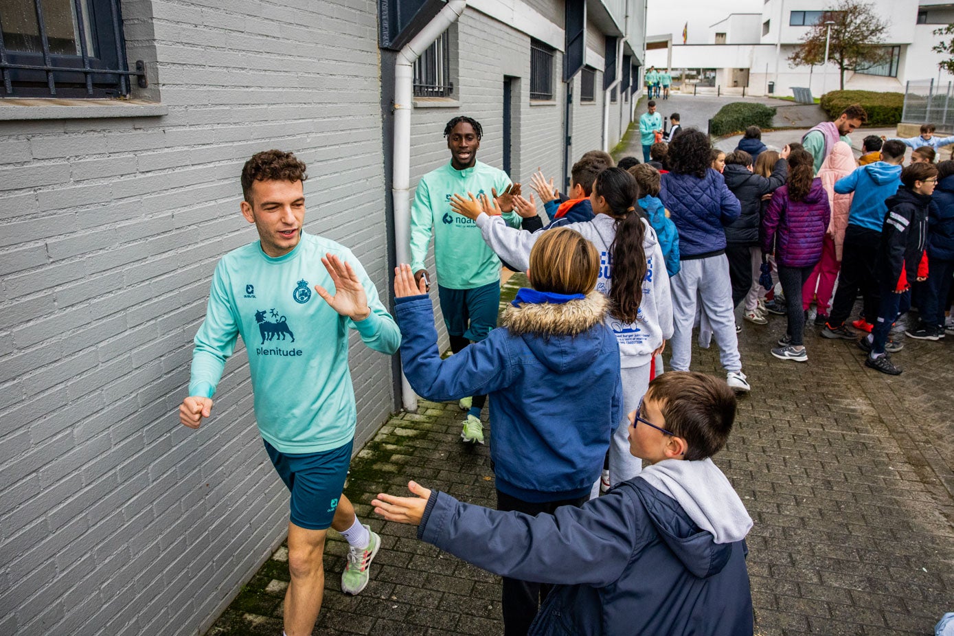 Íñigo Vicente y Lago Junior saludan a los niños del colegio Buenaventura González.