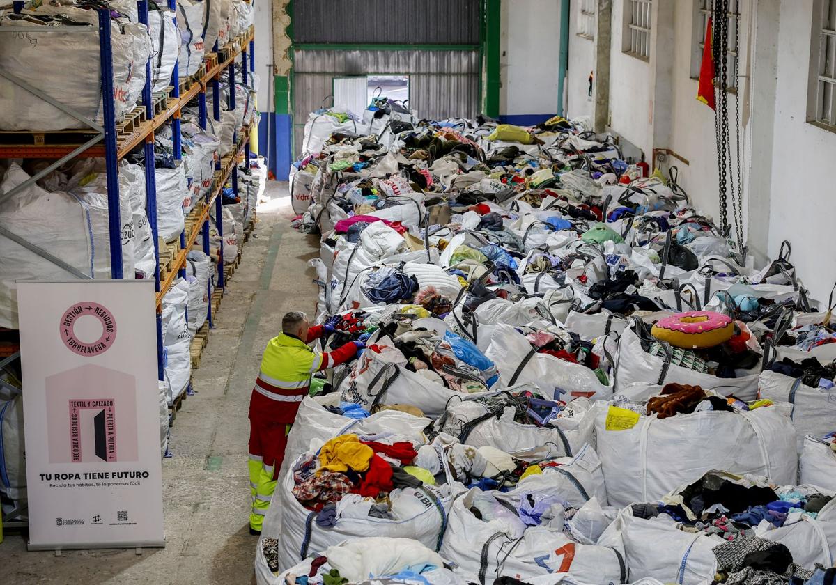 Un operario del servicio recoloca productos en una bolsa en el depósito de Barreda, que almacena unas 16 toneladas de ropa desde julio.