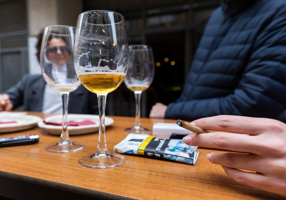 Un grupo de personas toma unas cañas y fuma en una terraza.