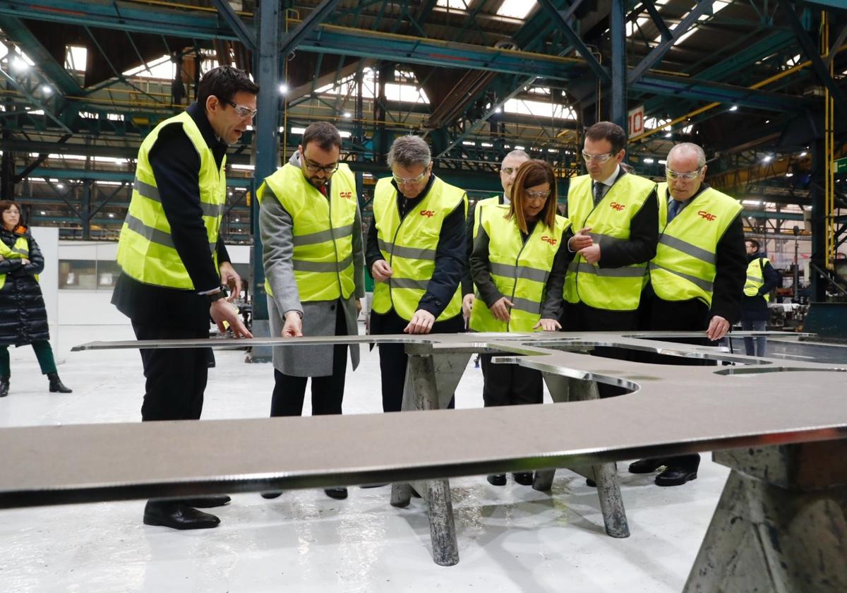 María José Sáenz de Buruaga y Adrián Barbón, junto a otras autoridades, en el acto de corte de la primera pieza de los nuevos trenes.