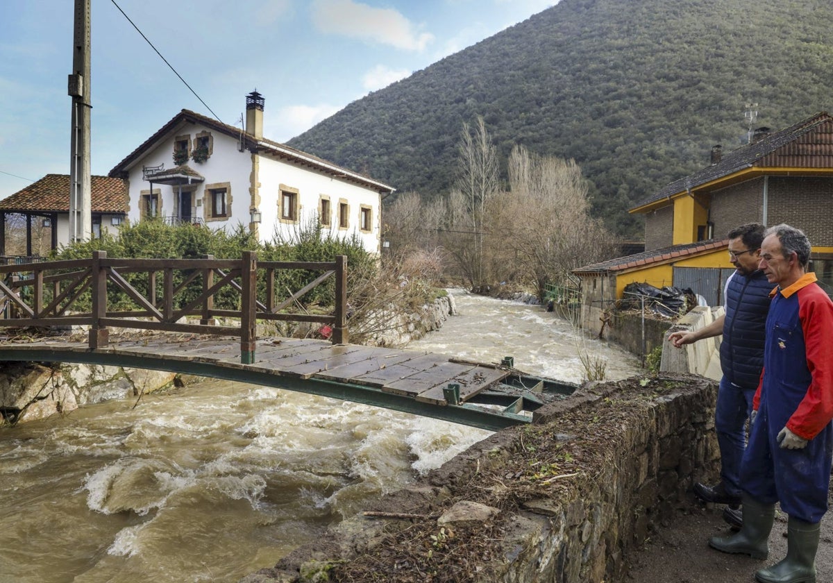 Dos vecinos observan la crecida del río Quiviesa a su paso por Vega de Liébana.