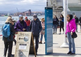 Un grupo de turistas observa uno de los carteles ubicados en el paseo marítimo de Santander.