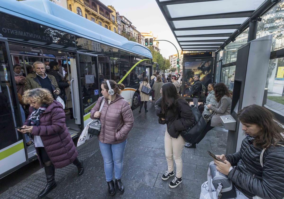 Un grupo de usuarios del TUS espera en la parada frente a la plaza del Ayuntamiento de Santander.