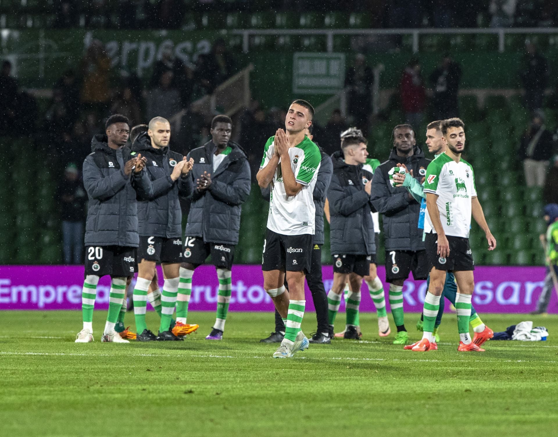 Los jugadores del Racing, con caras largas, saludan al público. 