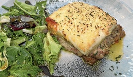 Lasaña de carne con bechamel sobre fondo de tomate y gratinada al horno.