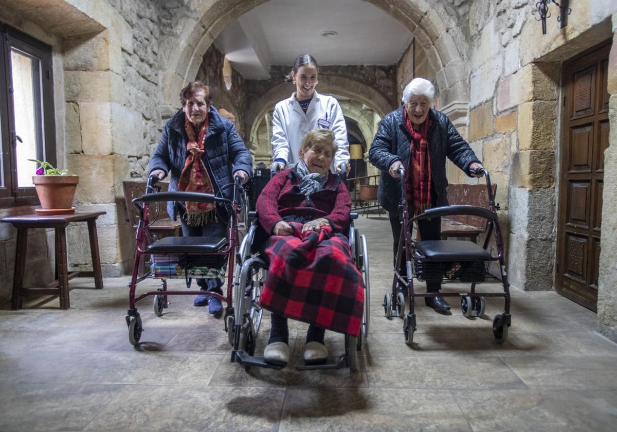 Adoración y Eva atraviesan el patio interior de la residencia San Francisco con sus andadores. Entre ellas, la educadora social, que lleva a Encarna en silla de ruedas.