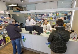 Varios clientes compran ayer antigripales en una farmacia de Santander.