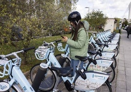 Una joven utiliza la aplicación móvil para alquilar una bicicleta eléctrica municipal.