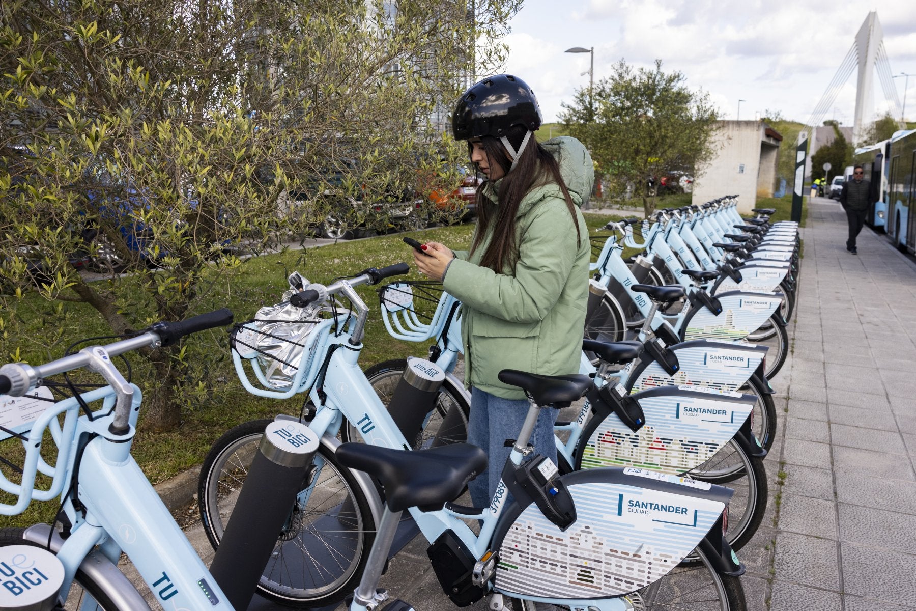 Una joven utiliza la aplicación móvil para alquilar una bicicleta eléctrica municipal.