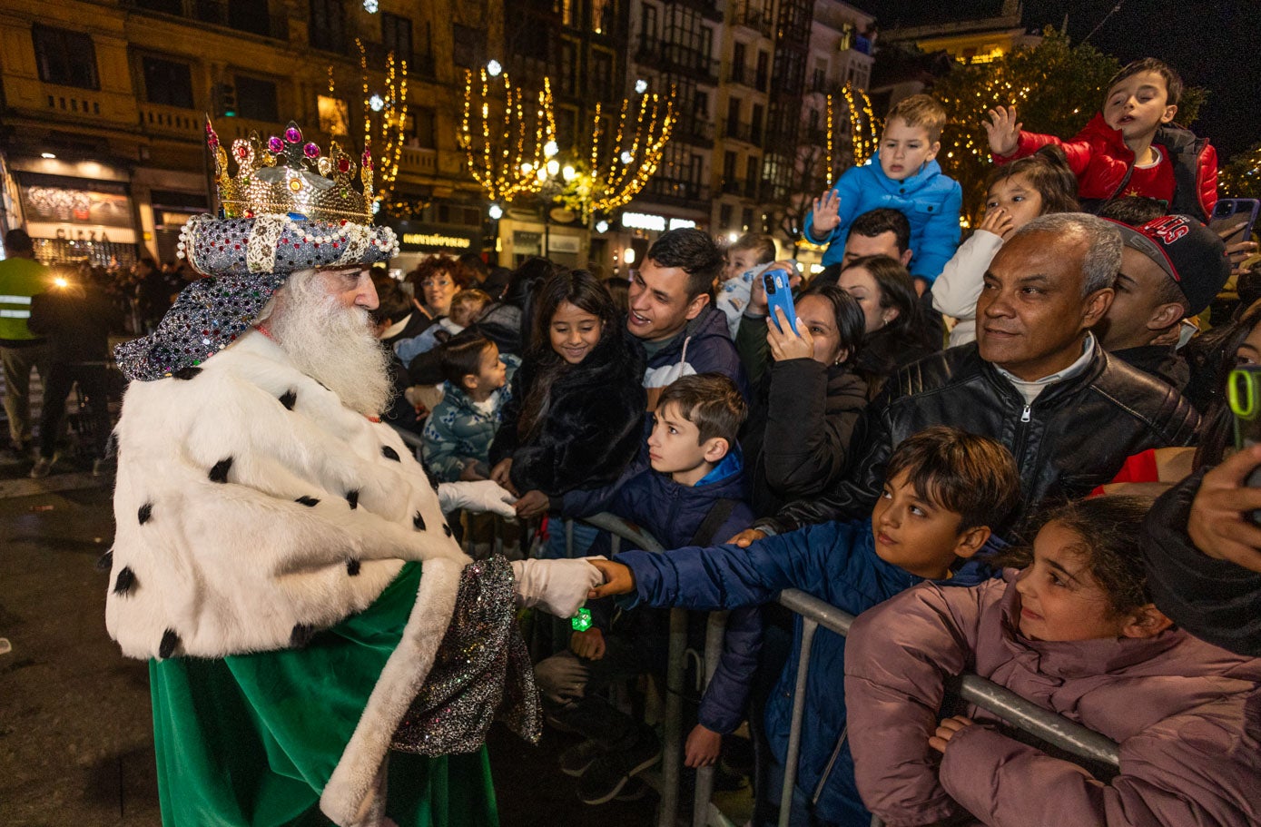 Melchor da la mano a un niño ante la atenta mirada de los demás, que lo saludaban y lo fotografíaban.