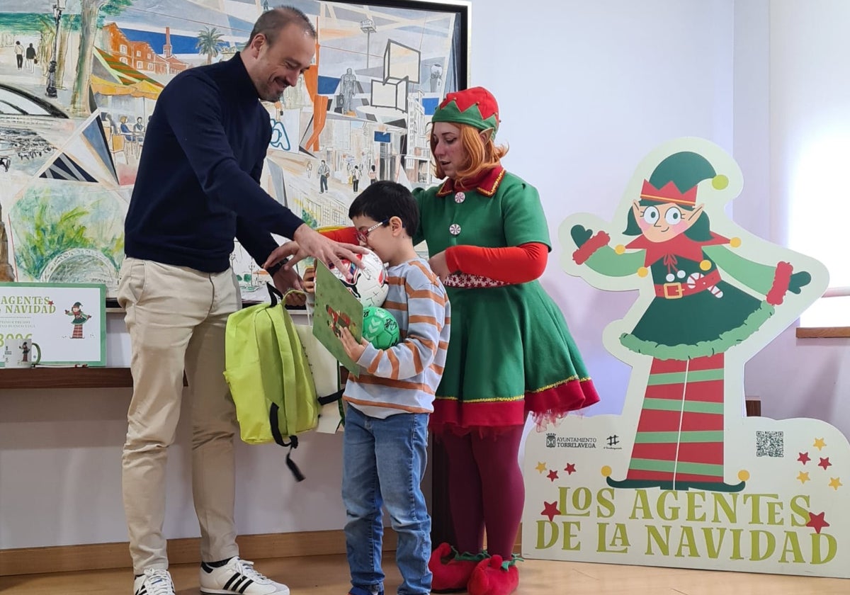 El ganador del concurso, Quino Blanco (centro), recibe los regalos del certamen de la mano del alcalde, Javier López Estrada, y la duendecilla Cascabel.