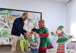 El ganador del concurso, Quino Blanco (centro), recibe los regalos del certamen de la mano del alcalde, Javier López Estrada, y la duendecilla Cascabel.