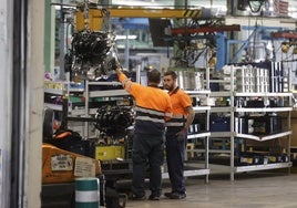 Dos trabajadores del sector industrial trabajan con maquinaria.