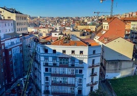 Los bomberos trabajan en la extinción del incendio desde el tejado del edificio de Juan de la Cosa