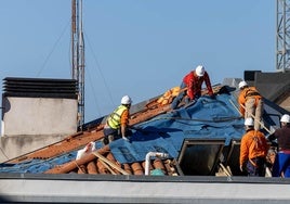 Los operarios, ayer, trabajan en el edificio de Juan de la Cosa, para cerrar un agujero que presentaba el tejado tras el incendio.