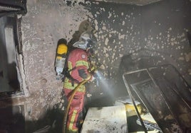 Un bombero actúa sofocando el fuego de la vivienda afectada.