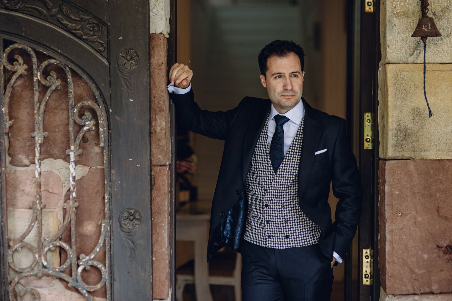 Momentos antes de casarse con Elena Heras en la Finca San Juan, Enrique Samperio posa para el reportaje de boda con un elegante traje azul marino y chaleco cruzado en tejido diseño pata de gallo.