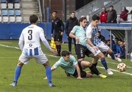 Alberto Gómez aguanta la entrada de dos futbolistas del Escobedo.