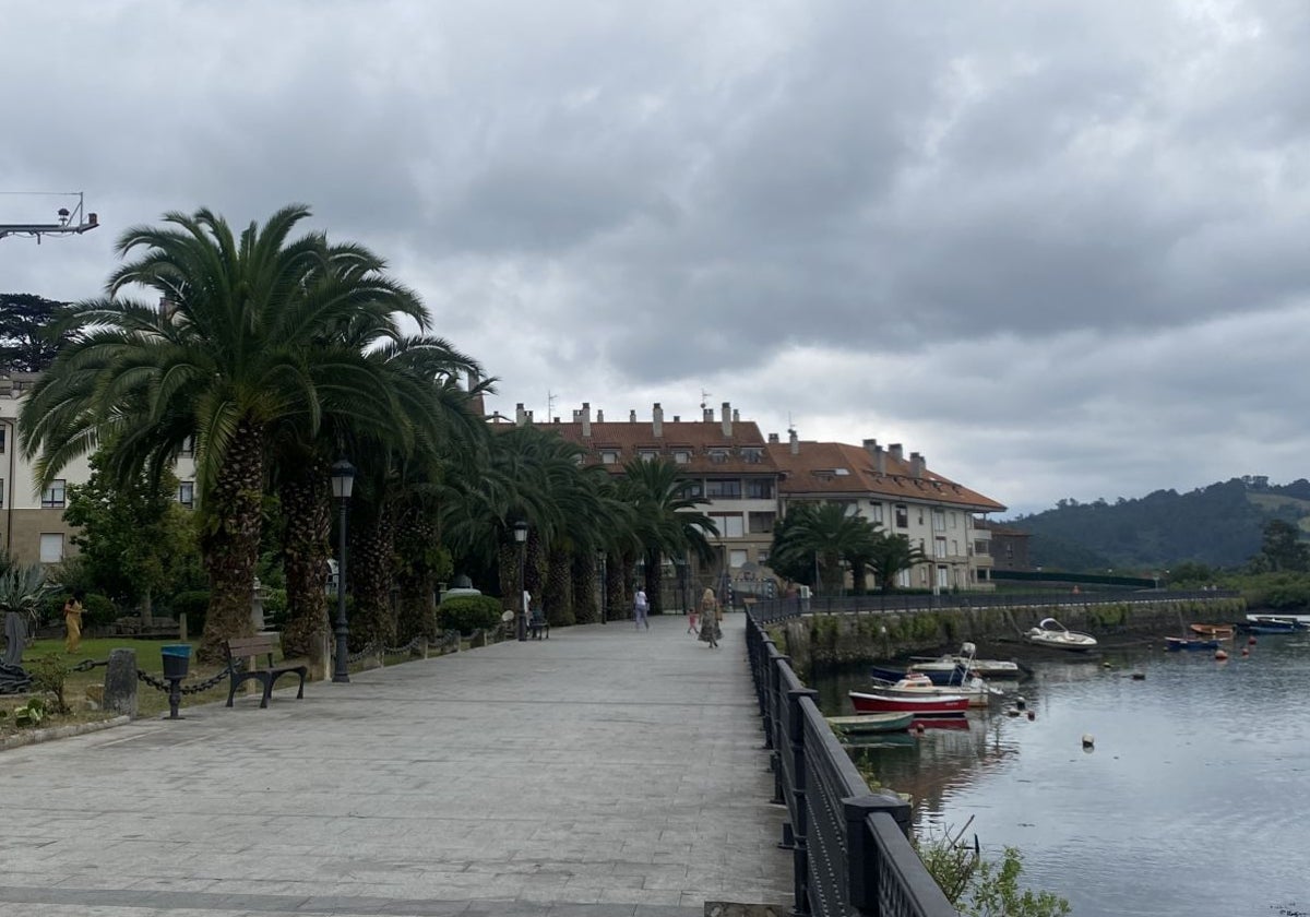 Algunos transeúntes caminan por el paseo de la ría de Limpias.