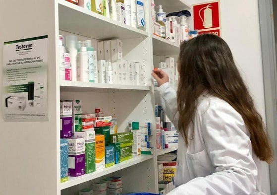 Personal de una farmacia de Cantabria repone los productos en una estantería.