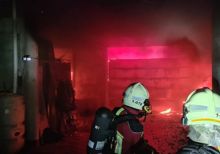 Bomberos sofocando el fuego del garaje.