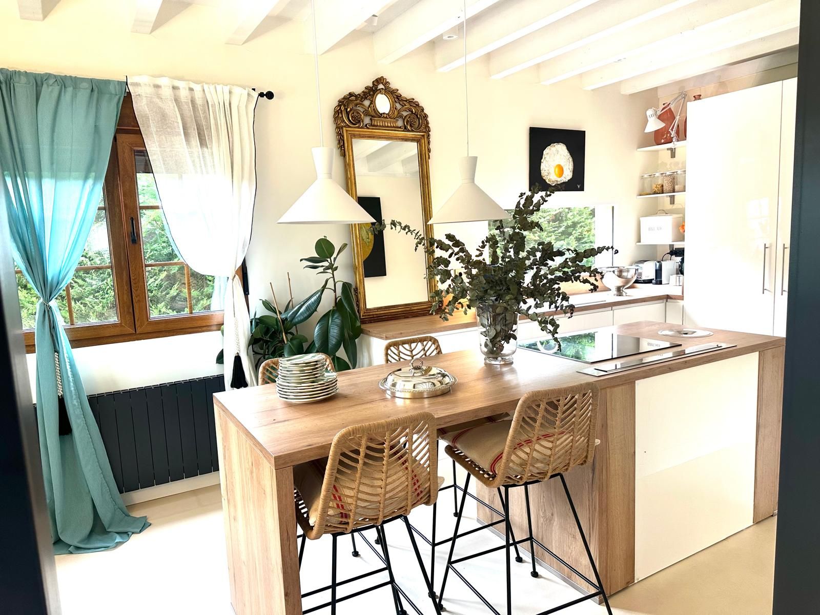 Los elementos de diseño como las cortinas y un gran espejo sirven para integrar esta cocina al resto de la casa.