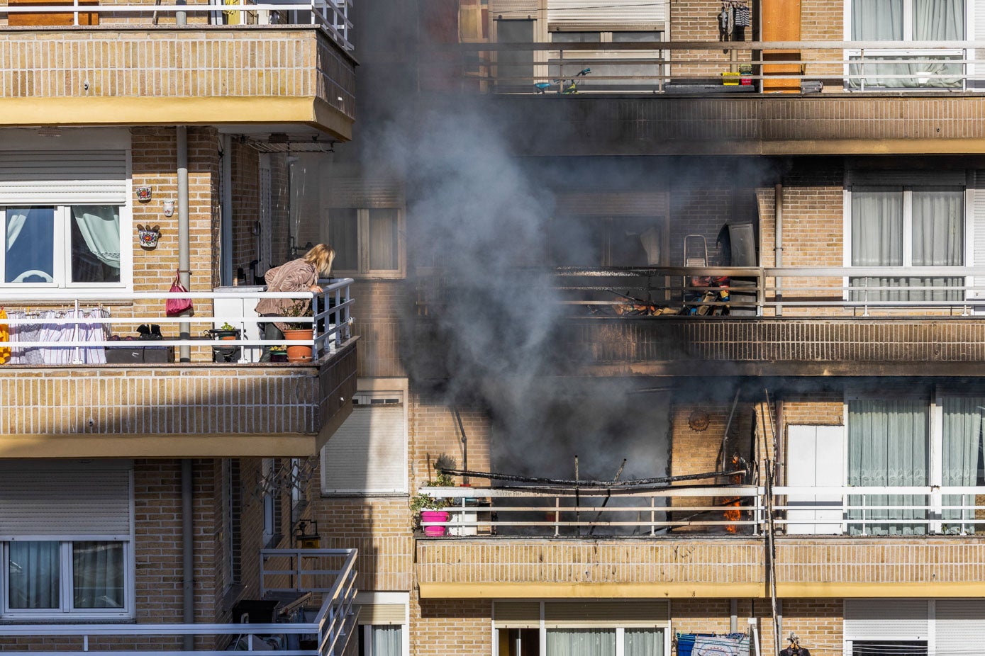 Una vecina asiste, desde su terraza, a la evolución del incendio, este jueves, en la Avenida del Besaya del Barrio Covadonga. 